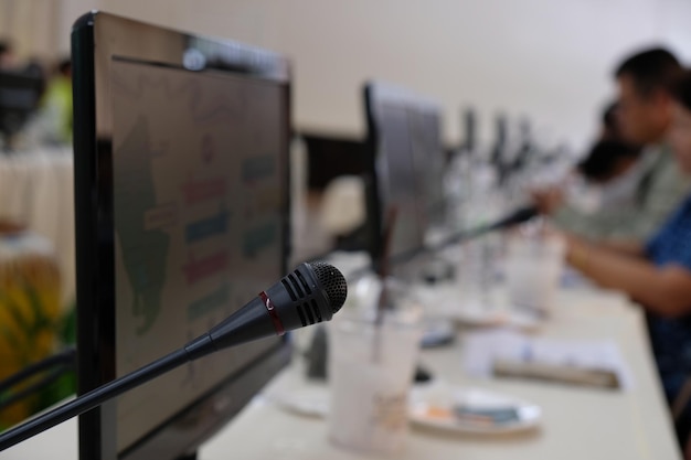 Photo close-up of microphone by computer monitor at desk in office