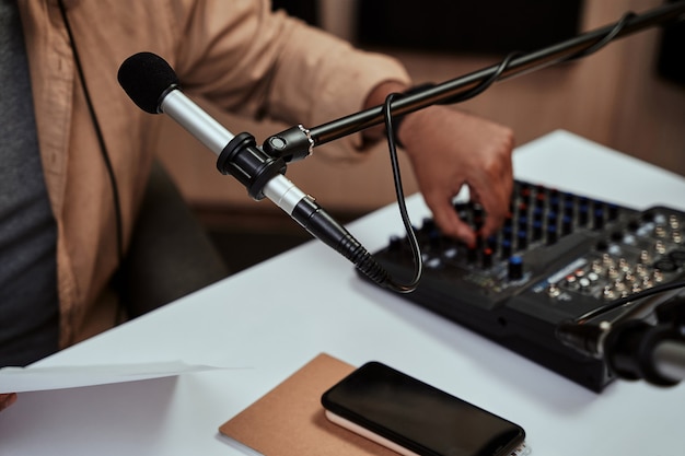 Close up of microphone at radion station studio male host working on a sound mixing desk in studio