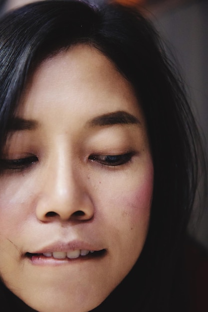 Photo close-up of mid adult woman biting lip while looking away