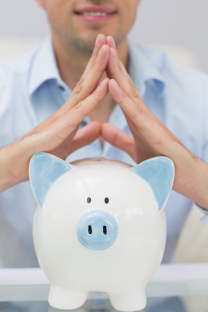 Close-up mid section man with piggy bank at home