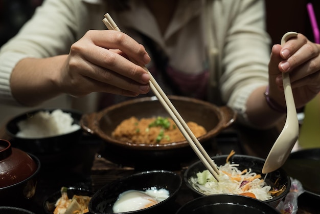 Foto close-up middelste deel van een vrouw die met eetstokjes aan tafel eet