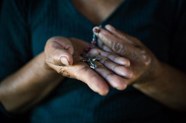 Close-up midsection woman holding rosary beads