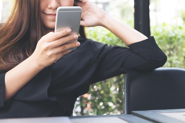 Close-up midsection of woman using mobile phone at table in cafe