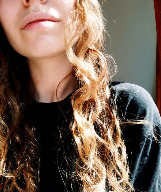 Close-up midsection of young woman with curly hair at home