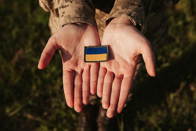Close up military woman hold velcro patch with flag of\
ukraine