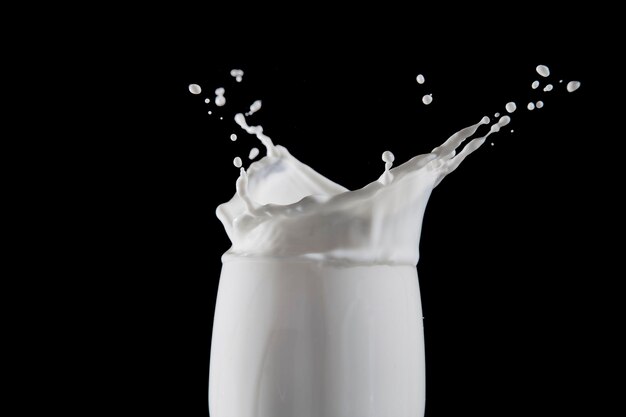 Photo close-up of milk splashing in glass against black background