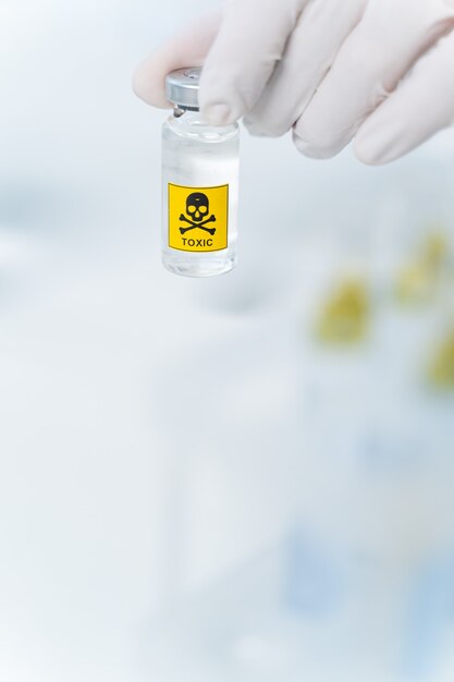 Close up of mini bottle with toxic liquid on the foreground, science and research concept