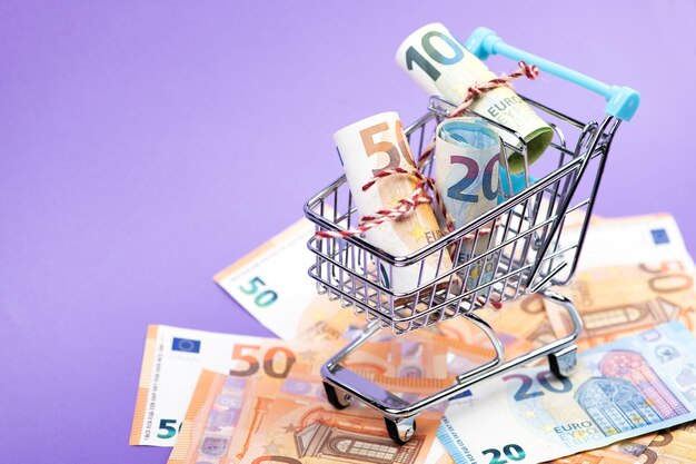 Close-up of miniature shopping cart with model house and icons against white background