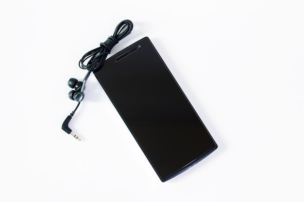 Photo close-up of mobile phone and headphones over white background