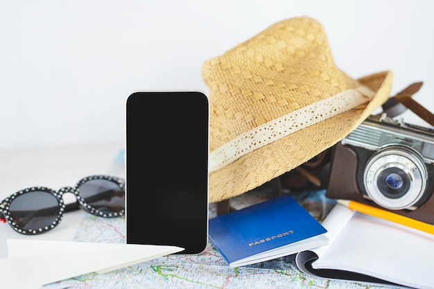 Close up of mobile phone, straw hat, vintage film camera and passport. Vacation concept