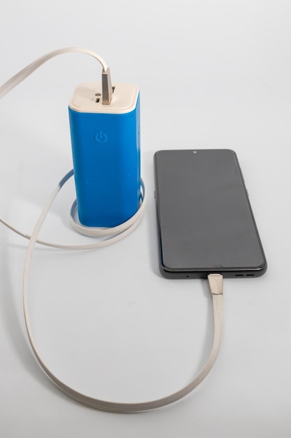 Foto close-up di un telefono cellulare con power bank sul tavolo su sfondo bianco