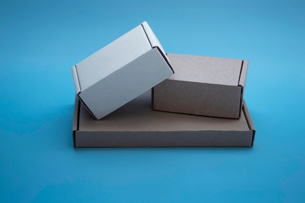 Close-up mock-up of cardboard boxes with copy space. Three corton boxes: brown and white on a blue background. Concept for packaging, gifts, delivery.