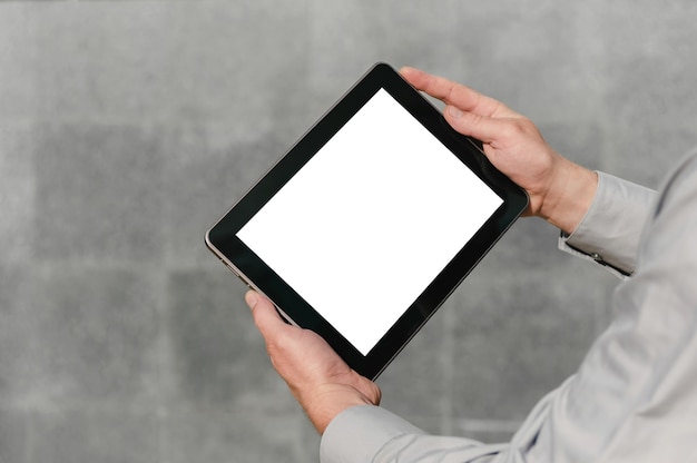 Photo close up, mock up tablet, in hands, of a person. against the background of a concrete wall.