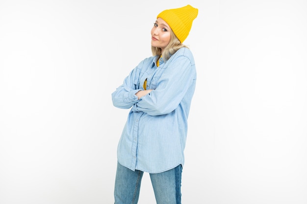 Close-up of a model girl in a stylish denim shirt with a blonde haircut on a white studio background.