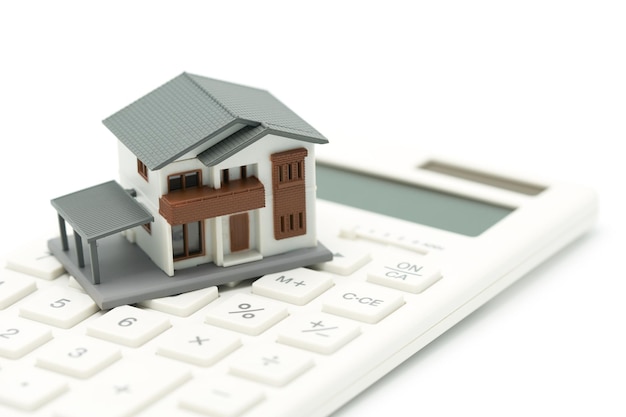 Close-up of model home with calculator over white background