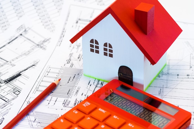 Close-up of model house and calculator on blueprints