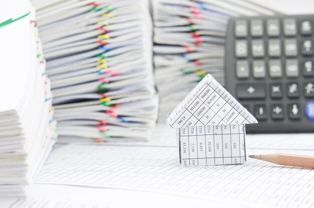 Крупный план модельного дома с калькулятором и карандашом на финансовых документах