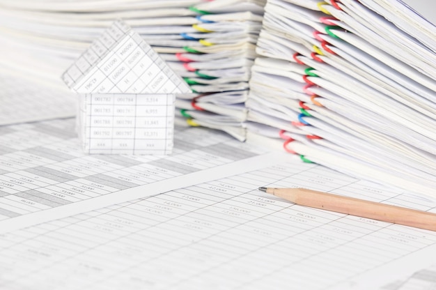 Photo close-up of model house with pencil on financial documents