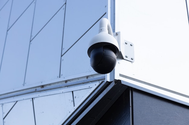 Close-up of modern video monitoring camera on white building