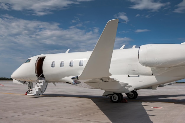 Крупный план современного белого частного самолета с открытой дверью трапа на перроне аэропорта