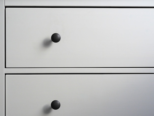 Primo piano di una cassettiera moderna in legno bianco con maniglie nere. minimalismo, interni moderni