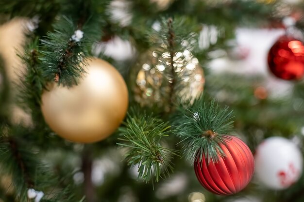 Close-up mooie groene kerstboomtak versierd met speelgoedballen van goud en rode soft focus