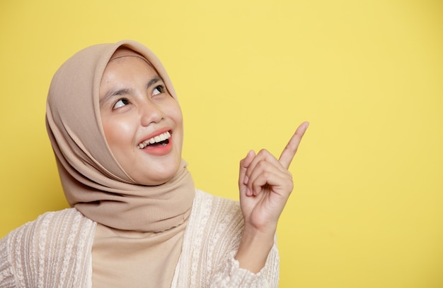 Close-up mooie hijab vrouwen glimlach expressie gelukkig iets goed idee wijzend op lege ruimte geïsoleerd op gele achtergrond