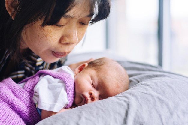 Photo close-up of mother by daughter sleeping on bed