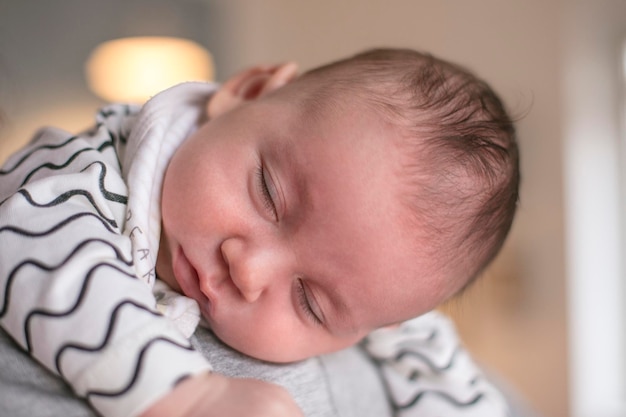 Close-up of mother carrying sleeping baby boy at home