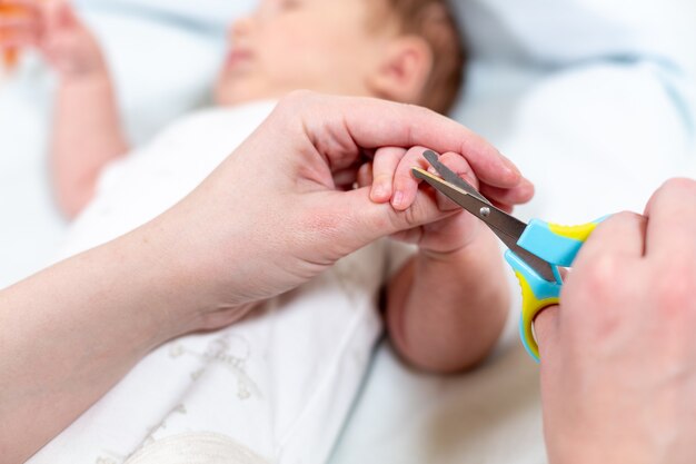 Chiuda in su dei chiodi dei bambini di taglio della madre con le forbici. allattare un bambino.