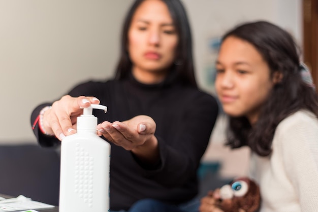 Close up mother and daughter cleaning their hands at home with sanitizer gel.