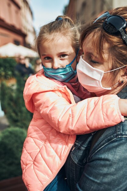 Foto close-up di madre e figlia che indossano una maschera in piedi all'aperto