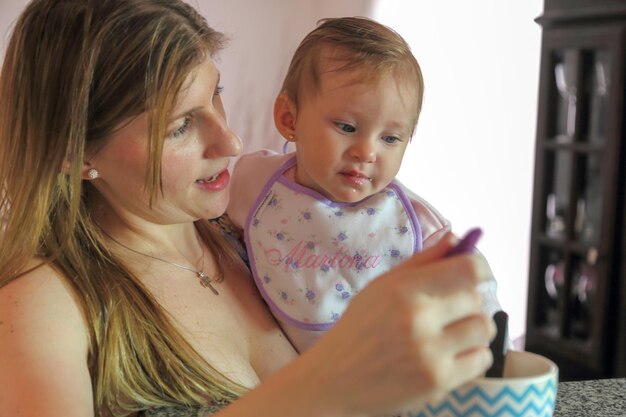 Photo close-up of mother feeding food to daughter at home