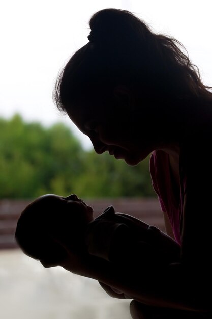 Foto close-up di una madre che tiene in braccio il bambino mentre è all'aperto