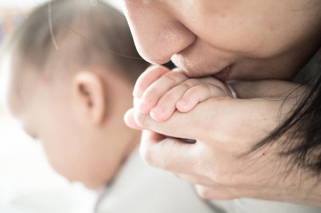 Photo close-up of mother kissing baby girl at home