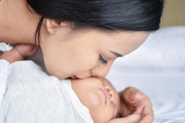 Photo close-up of mother kissing daughter on bed at home