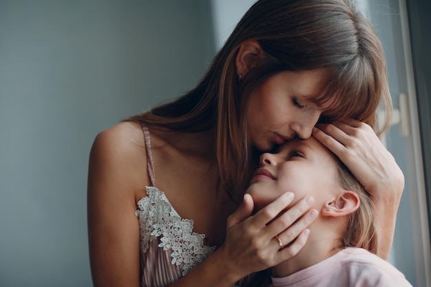 Foto close-up di una madre che bacia sua figlia a casa