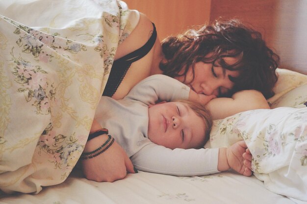 Photo close-up of mother and son sleeping on bed