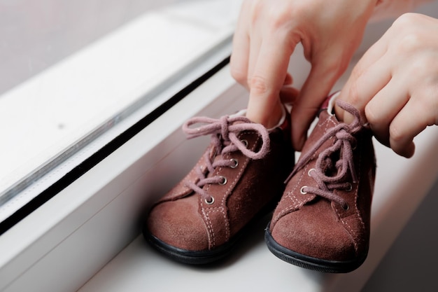 Primo piano di mani di una madre stanno giocando con scarpe da bambino mani femminili che mostrano scarpe da bambina