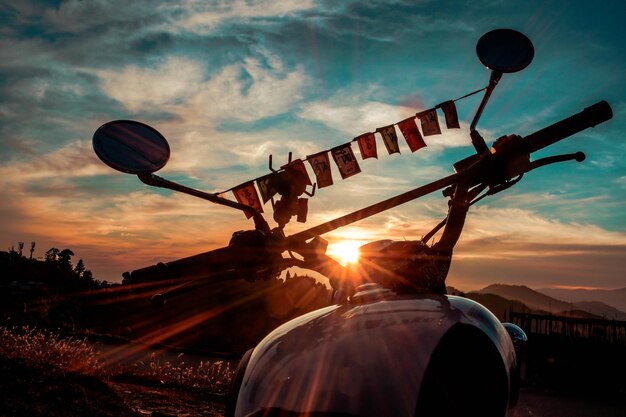 Close-up of motorcycle against sky during sunset