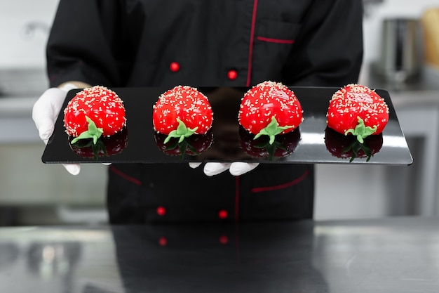 Close-up of mousse cakes in the hands of a pastry chef.