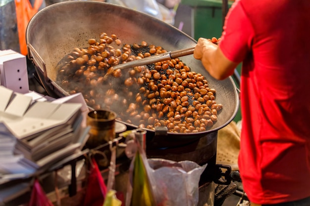 Close up movement hand a man worker roasting chestnuts in street chinatown 