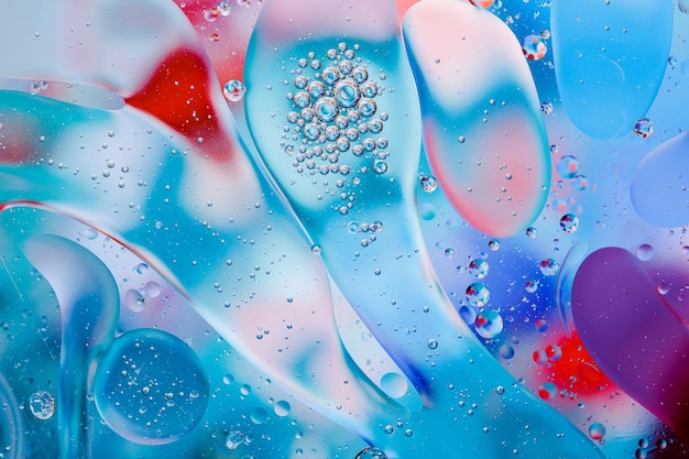 Close-up of the movement of oil droplets on the water surface. Colorful abstract macro background of oil drops on the water surface.