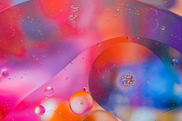 Close-up of the movement of oil droplets on the water surface. Colorful abstract macro background of oil drops on the water surface.