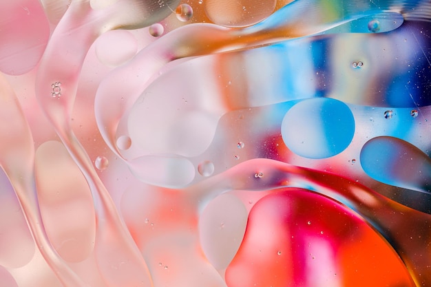 Close-up of the movement of oil droplets on the water surface. Colorful abstract macro background of oil drops on the water surface.