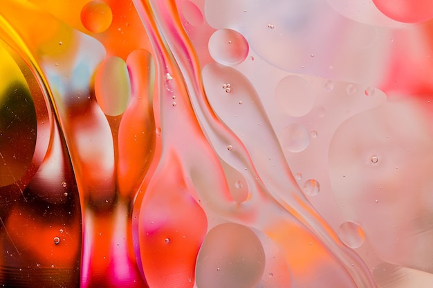 Close-up of the movement of oil droplets on the water surface. Colorful abstract macro background of oil drops on the water surface.