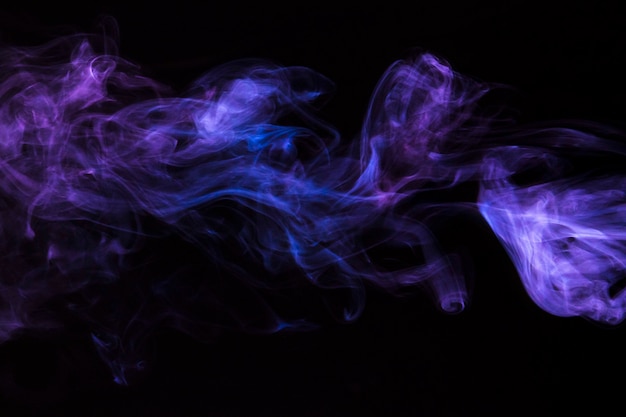 Close-up of movement of purple smoke on black background