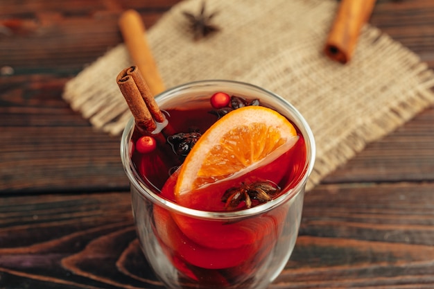 Close up of mulled wine cup with spices and berries on grey table