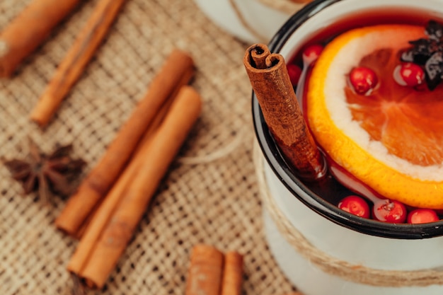 Close up of mulled wine cup with spices and berries on grey table