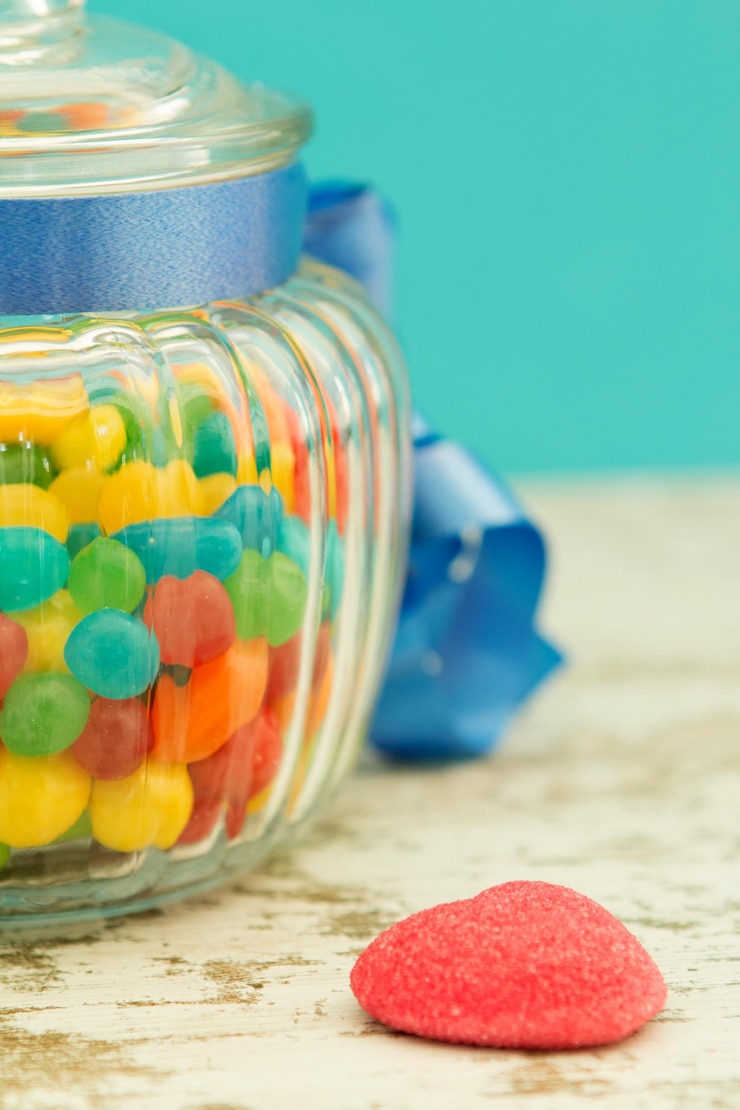 Photo close-up of multi colored candies in glass jar on table